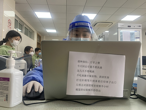 在接种台上的电脑,张贴了新冠疫苗接种前后的注意事项。